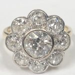 An 18ct round cluster head ring set with an early round brilliant cut diamond surrounded by 8 old cut diamonds