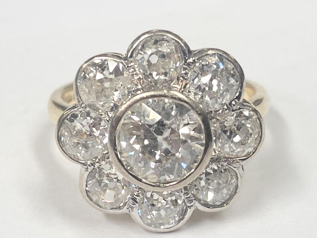 An 18ct round cluster head ring set with an early round brilliant cut diamond surrounded by 8 old cut diamonds